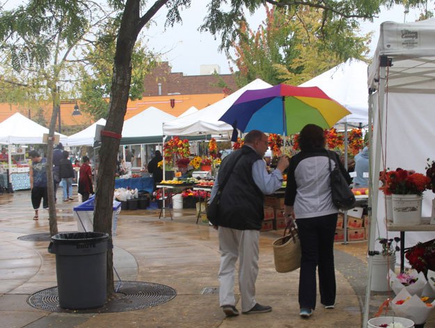 A couple shares an umbrella Tuesday at the Renton Farmers Market. Tuesday marks the market's final day this season.