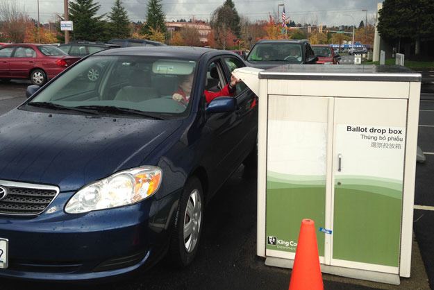 A voter drops off her ballot Tuesday at the King County elections office on Grady Way.