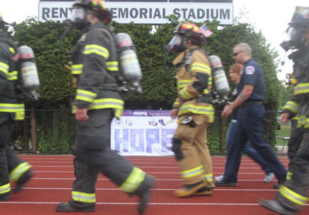 Renton firefighters walk past a 'Hope' sign at the Relay for Life Friday evening at Renton Memorial Stadium.