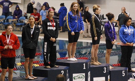 Hazen's Lauren Kaufman stands on top of the podium after her win in the 100-yard freestyle at the state swim meet.