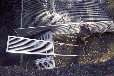 Gary Sprague  with Seattle Public Utilities describes  how a gate will easily open and close to allow Chinook salmon to move upriver of a weir on the Cedar River used to trap returning sockeye salmon. The weir is in the river next to Carco Theater in Cedar River Park.