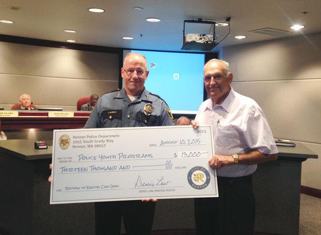 Police Chief Kevin Milosevich accepts a check from Return to Renton car show co-chair Jim Medzegian during the Aug. 10 City Council meeting.