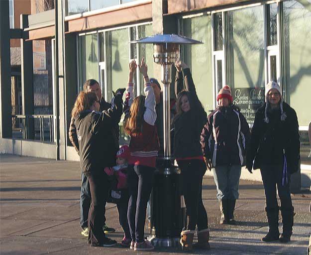 Revelers gather around a portable heater to stay warm at the Piazza prior to the tree lighting Dec. 7.