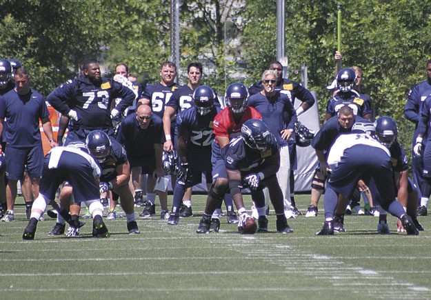 Quarterback Russell Wilson prepares to lead the offense through a drill under the watchful eye of Head Coach Pete Carroll during the team's minicamp in June.