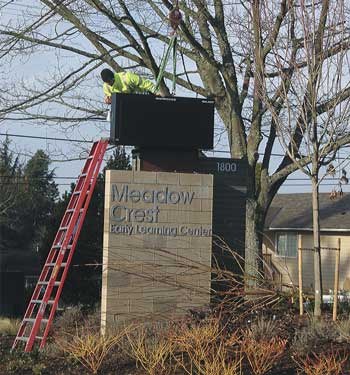 Workers install an electronic sign this past week at the Meadow Crest Early Learning Center.