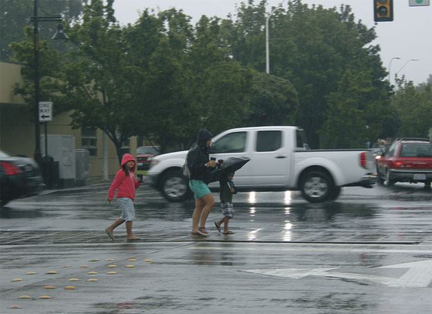 A family dodges raindrops during a downpour downtown on Wednesday. Don't worry though