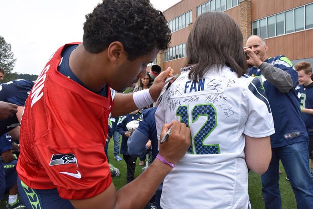 Seahawks quarterback Russell Wilson signs the jersey of a young fan during minicamp last week.