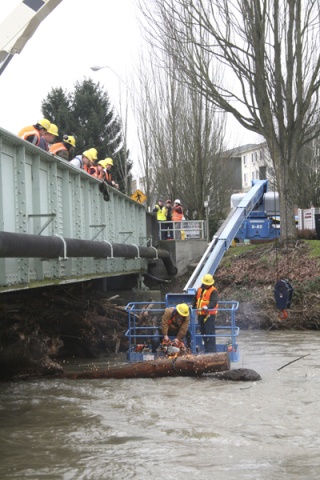 Sparks fly Friday morning as workers from King County cut a chain holding two logs together under the Williams Avenue bridge. Moments later