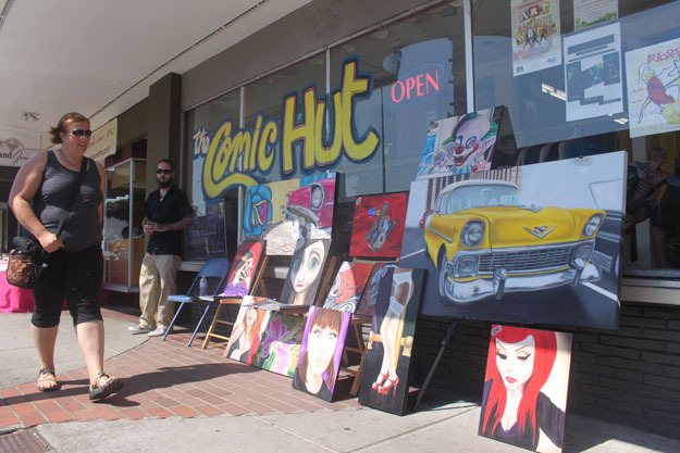 An artists displays his wares as a shopper walks by at the 2014 Art and Antique walk.