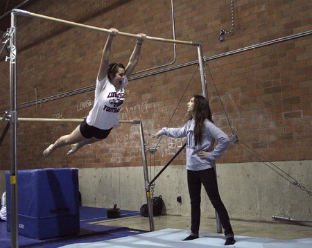 Lindbergh gymnast Kristina Batschi practices on the bars while coach Raquel Murray helps.