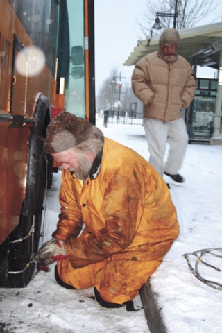 Metro Transit mechanic Scott Vissering chains up a small bus at Renton Transit Center Thursday.