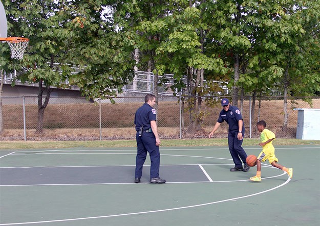 A pair of firefighters gets schooled on the basketball court by a young man Tuesday during National Night Out at Thomas Teasdale Park.