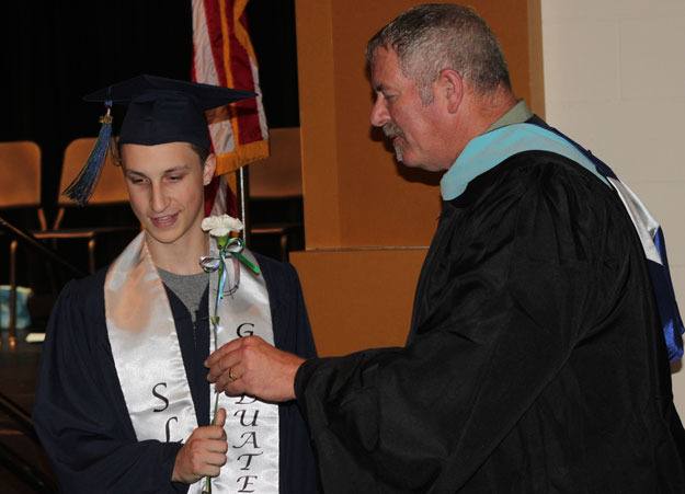 Principal Ron Mahan bestows a flower on a graduate from the Secondary Learning Center at the school's June 15 commencement ceremony.