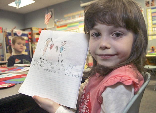 First grader Sharon Marsee holds up a story she wrote about Valentine’s Day last week