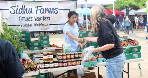 A customer buys strawberries from Sidhu Farms at the Renton Farmers Market. Bailey Jo Josie/Sound Publishing photo