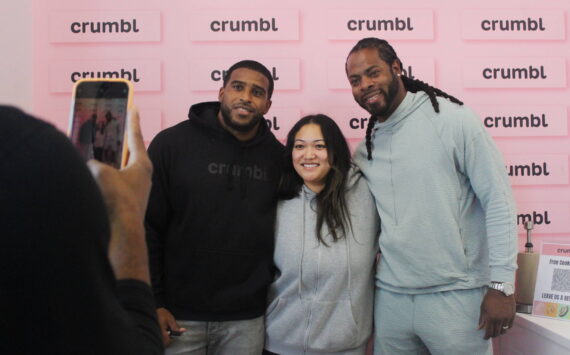 Bobby Wagner and Richard Sherman pose for a photo with a fan on the opening day of Crumbl Cookies, which Wagner co-owns. Photo by Bailey Jo Josie/Sound Publishing.