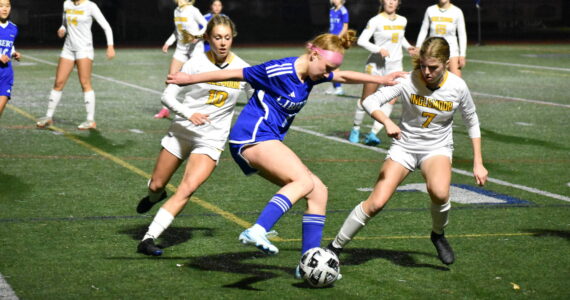 Morgan Ackermann controls the ball between two Inglemoor defenders. Ben Ray / The Reporter