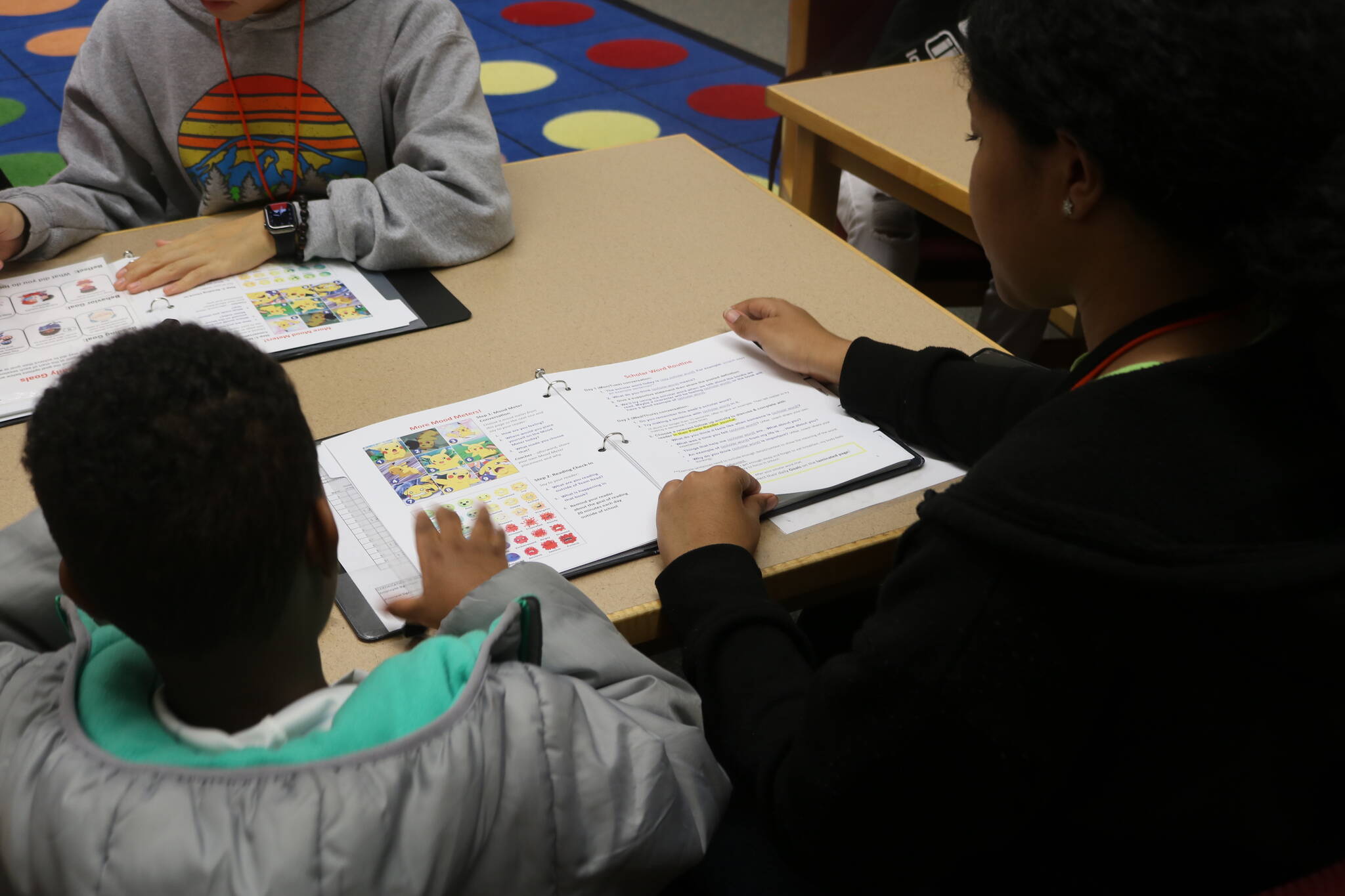 Before reading begins, coaches check-in with students on how their doing with little workbooks. Photo by Bailey Jo Josie/Sound Publishing.