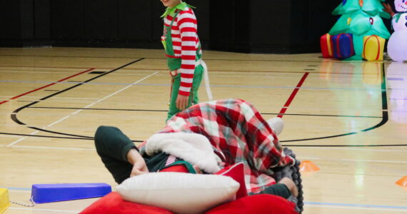 Photo by Bailey Jo Josie/Sound Publishing.
One of the cadets from the annual Elf Academy tries to sneak around the sleeping head elf without waking him up. Cadets have to go through an obstacle course with bells on their belt without being too loud. The Elf Academy took place Saturday, Dec. 14. Photo by Bailey Jo Josie/Sound Publishing.