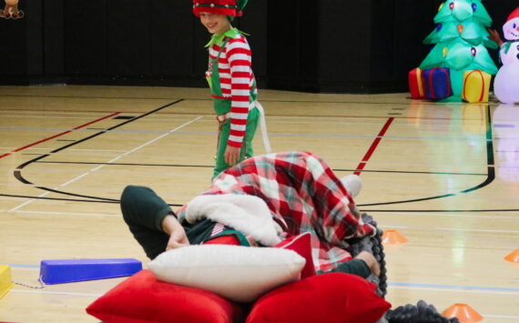 Photo by Bailey Jo Josie/Sound Publishing.
One of the cadets from the annual Elf Academy tries to sneak around the sleeping head elf without waking him up. Cadets have to go through an obstacle course with bells on their belt without being too loud. The Elf Academy took place Saturday, Dec. 14. Photo by Bailey Jo Josie/Sound Publishing.